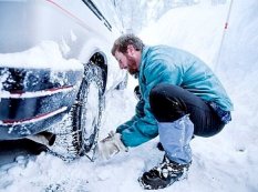 An everyday athlete putting chains on a tire.