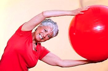 Active adult woman using stability ball.