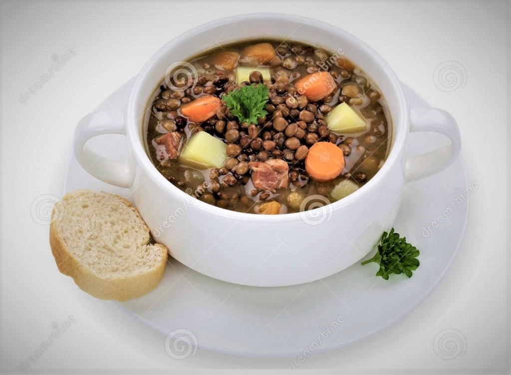 A bowl of cooked lentil and buckwheat with carrots, potatoes and broccoli, and a slice of artisan bread on the side.