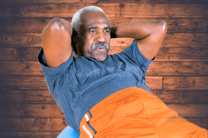 Black man wearing blue t-shirt, doing abs on a fit ball for active adults 55+