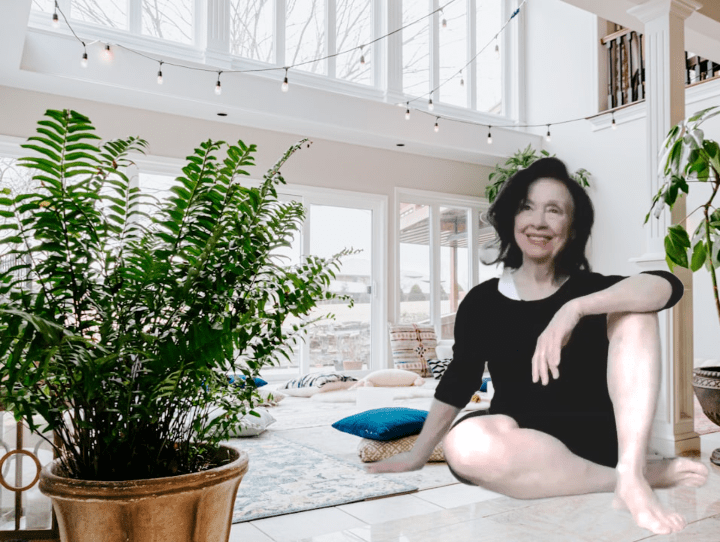 Irene Pastore, Yoga & Pilates Instructor, sitting in a mind/body studio surrounded by green plants in a white room,, smiling and approachable for active agers.